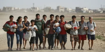 Migrants walking on a dusty road, representing the global migration crisis